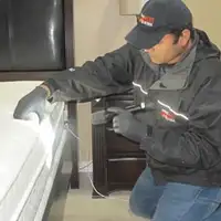 Bed bug inspection technician checking a mattress and bed frame for signs of infestation in Baltimore, MD