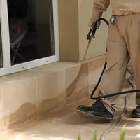 General pest control technician spraying exterior perimeter around a home in Baltimore, MD