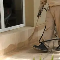 General pest control technician spraying exterior perimeter around a home in Baltimore, MD