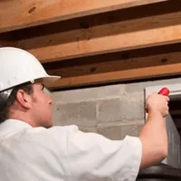 Termite inspection technician checking a basement wall and framing for termite activity in Baltimore, MD