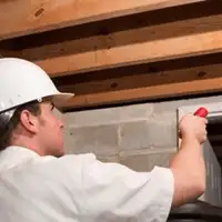 Termite inspection technician checking a basement wall and framing for termite activity in Baltimore, MD